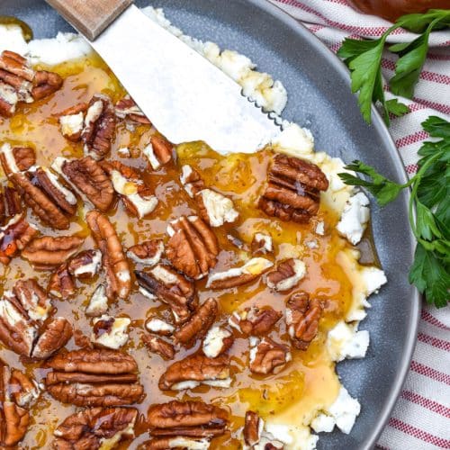 a cheese spreader scooping boursin cheese holiday party spread off a blue plate