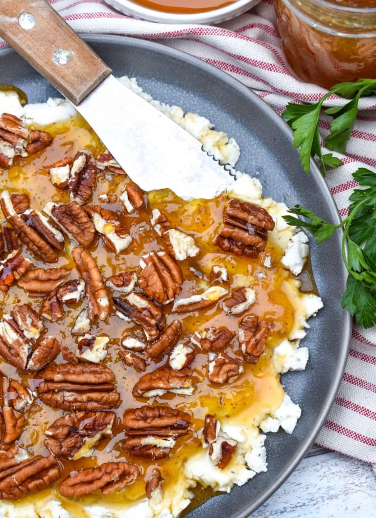a cheese spreader scooping boursin cheese holiday party spread off a blue plate