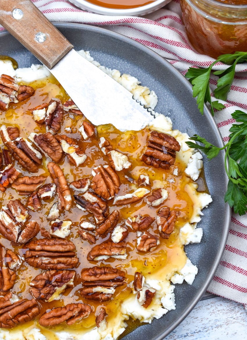 a cheese spreader scooping boursin cheese holiday party spread off a blue plate