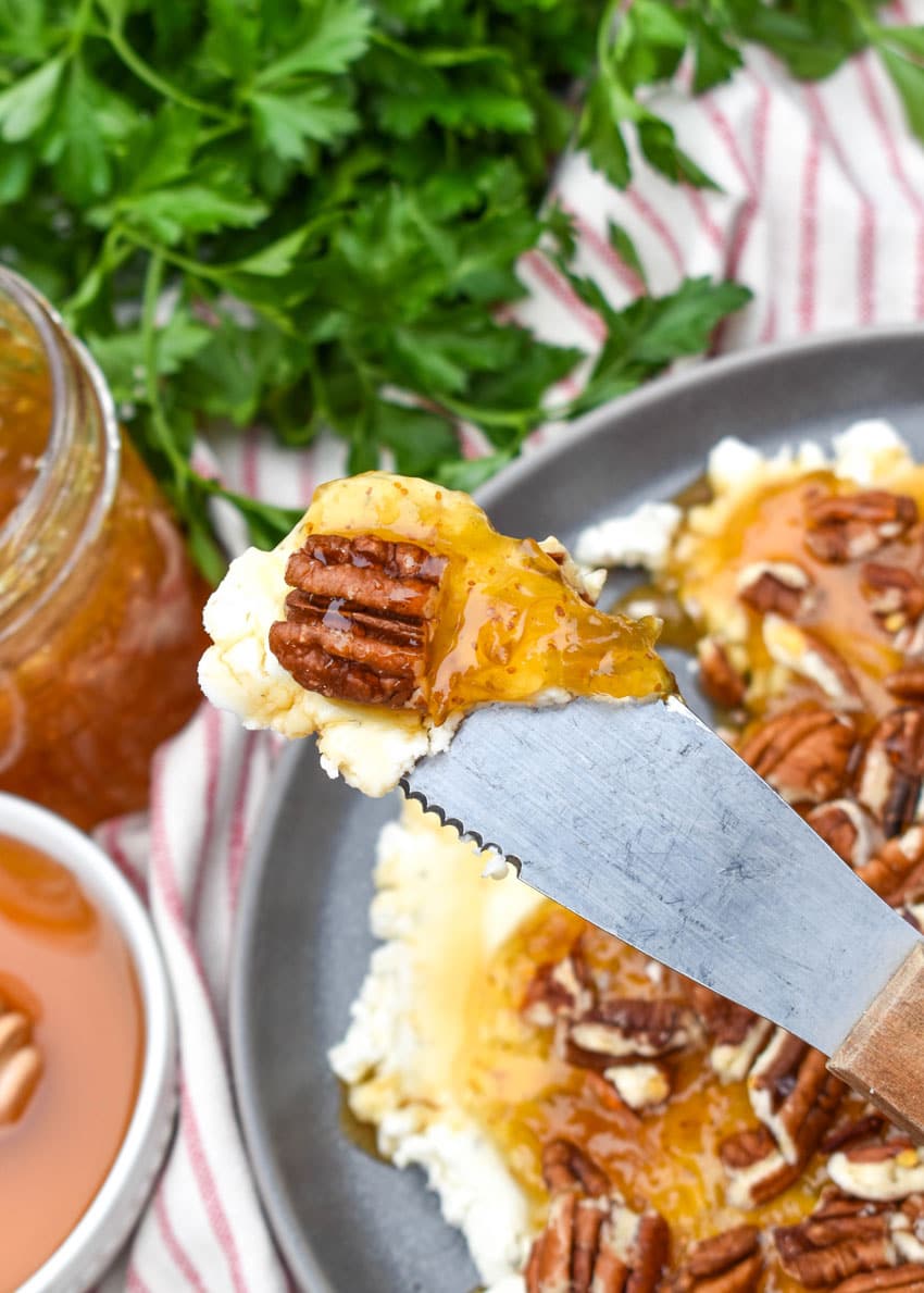a cheese spreader holding up a scoop of boursin cheese holiday party spread