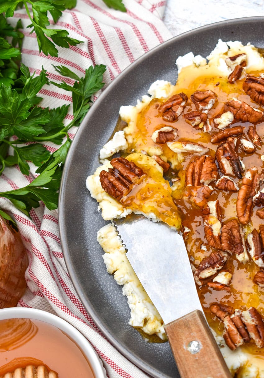 a cheese spreader scooping boursin cheese holiday party spread off a blue plate