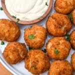 crispy crab balls on a white plate with a small bowl of creamy dip on the side