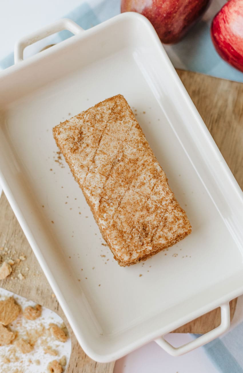 a cinnamon spice coated brick of cream cheese in a white baking dish