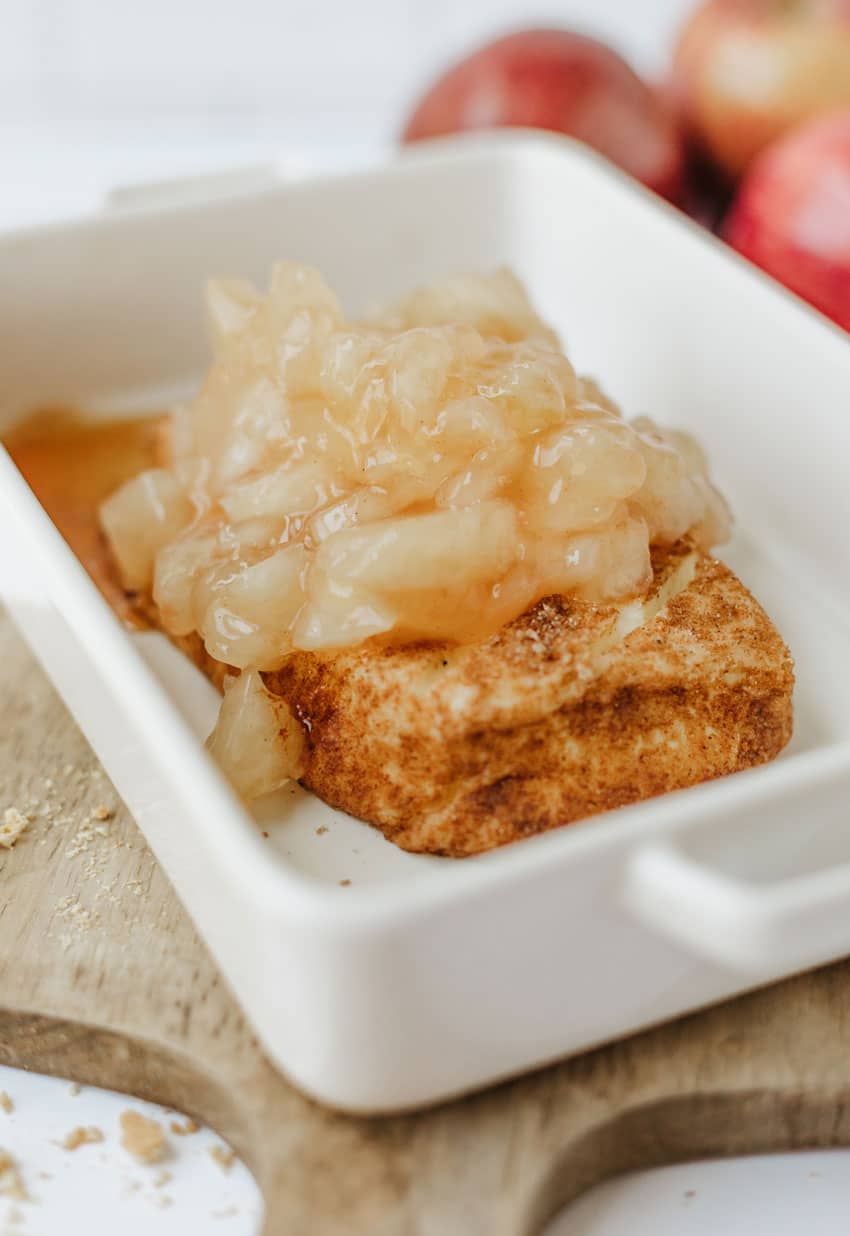 apple pie filling topped smoked cream cheese in a small white baking dish