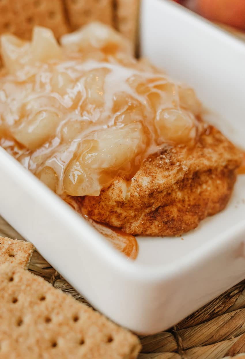 apple pie filling topped smoked cream cheese in a small white baking dish