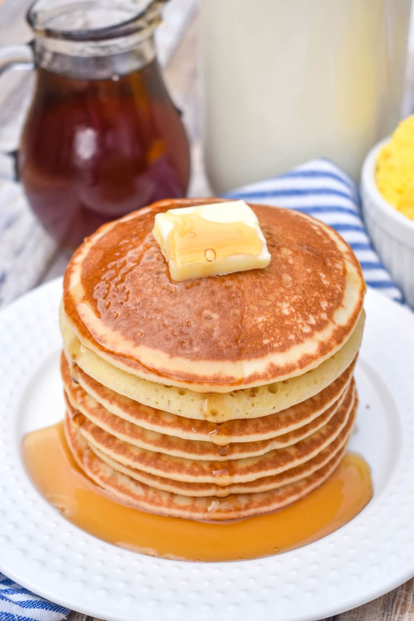 homemade maple syrup over a stack of pancakes on a white plate