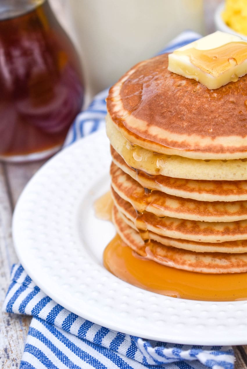 homemade maple syrup over a stack of pancakes on a white plate