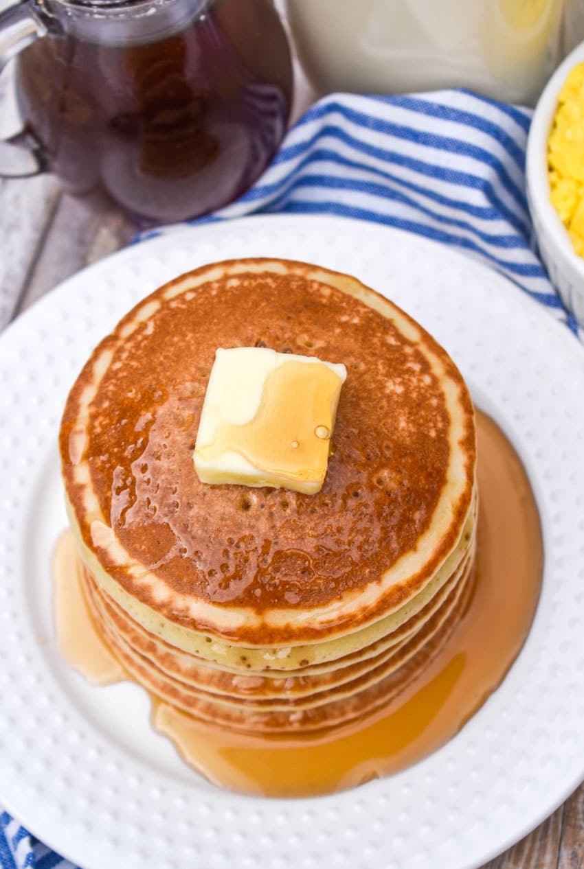 homemade maple syrup over a stack of pancakes on a white plate