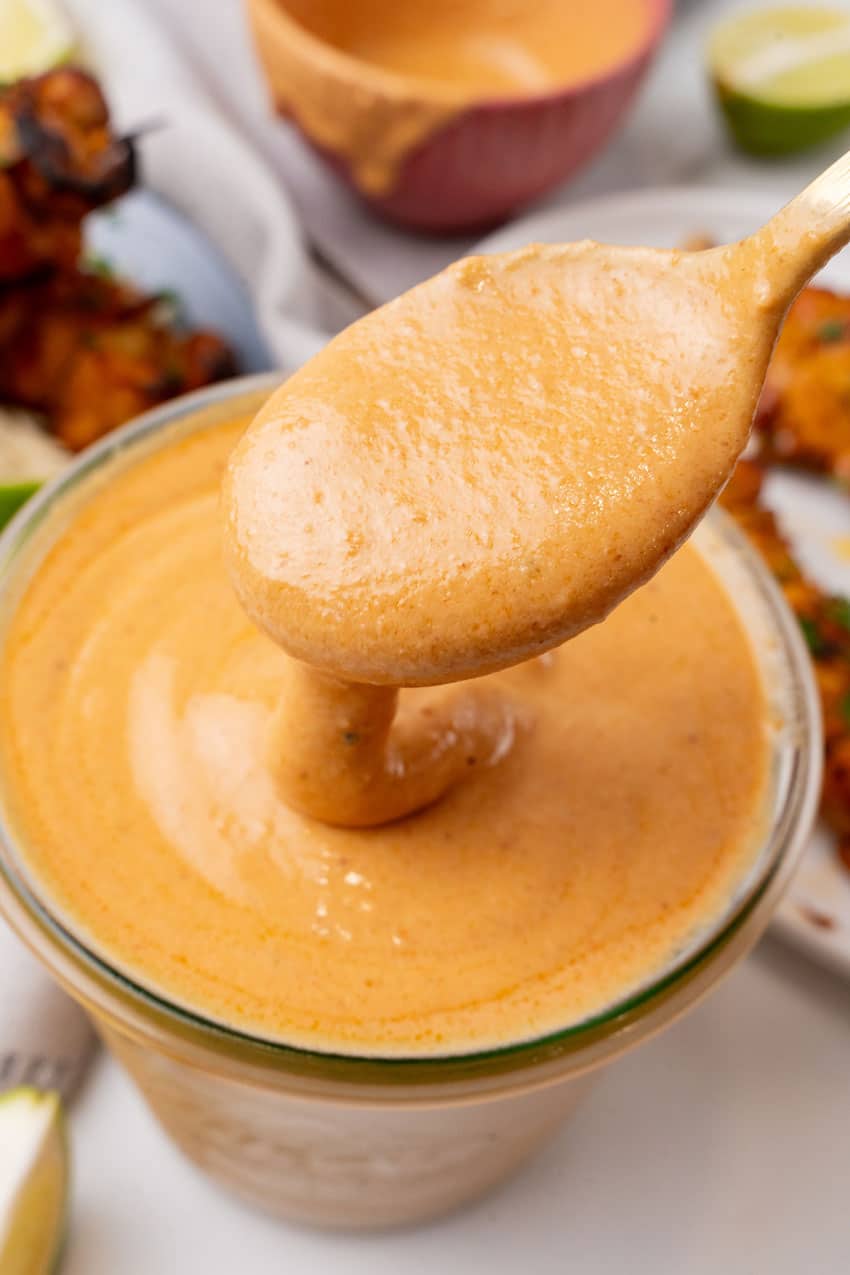 a spoon holding up a scoop of creamy peanut sauce