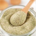 a wooden spoon scooping homemade ranch seasoning mix out of a small glass jar