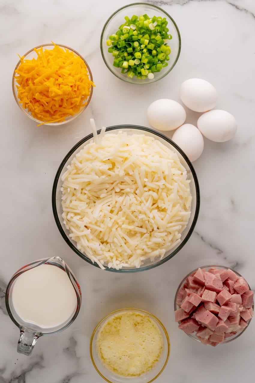 an overhead image showing the measured ingredients needed to make a hashbrown crust quiche with ham and cheese