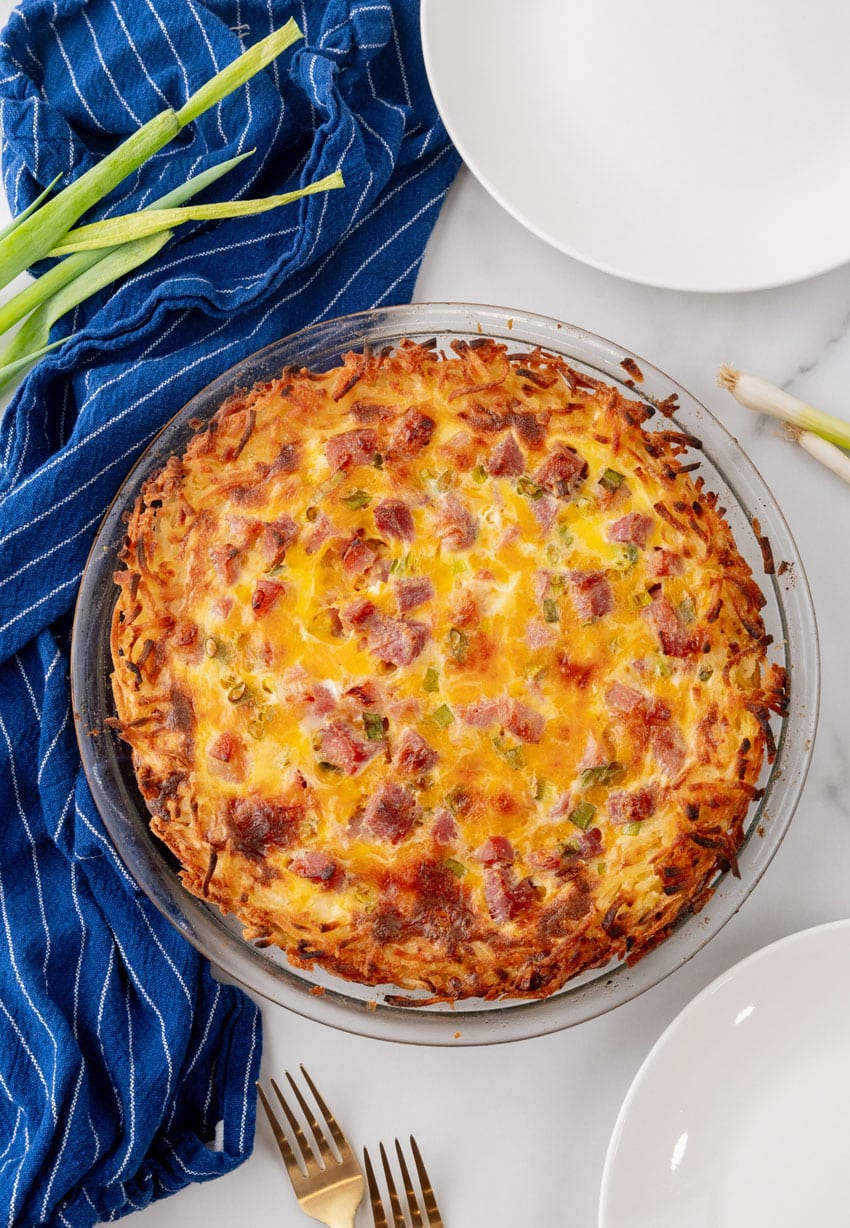 a ham and cheese hashbrown quiche in a glass pie plate