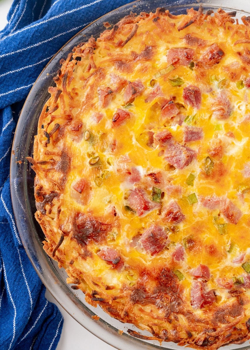 a ham and cheese hashbrown quiche in a glass pie plate