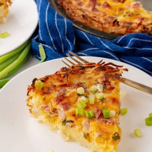 a slice of ham and cheese hash brown quiche on a white plate