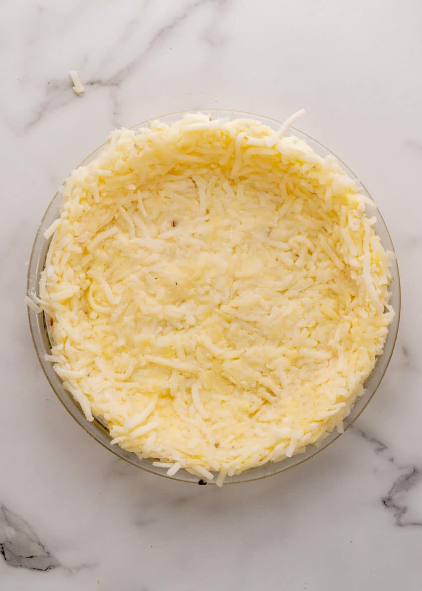 shredded hashbrowns pressed into the bottom of a glass pie plate