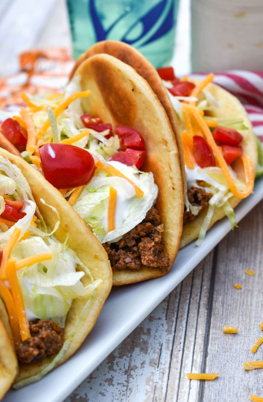 homemade beef chalupas arranged in a row on a white serving platter
