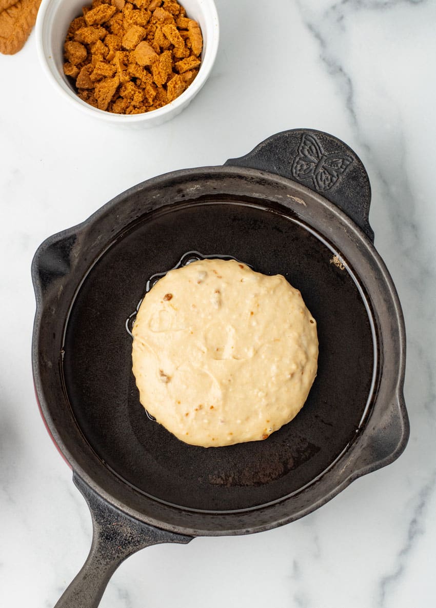 a cookie butter pancake frying in a large cast iron skillet