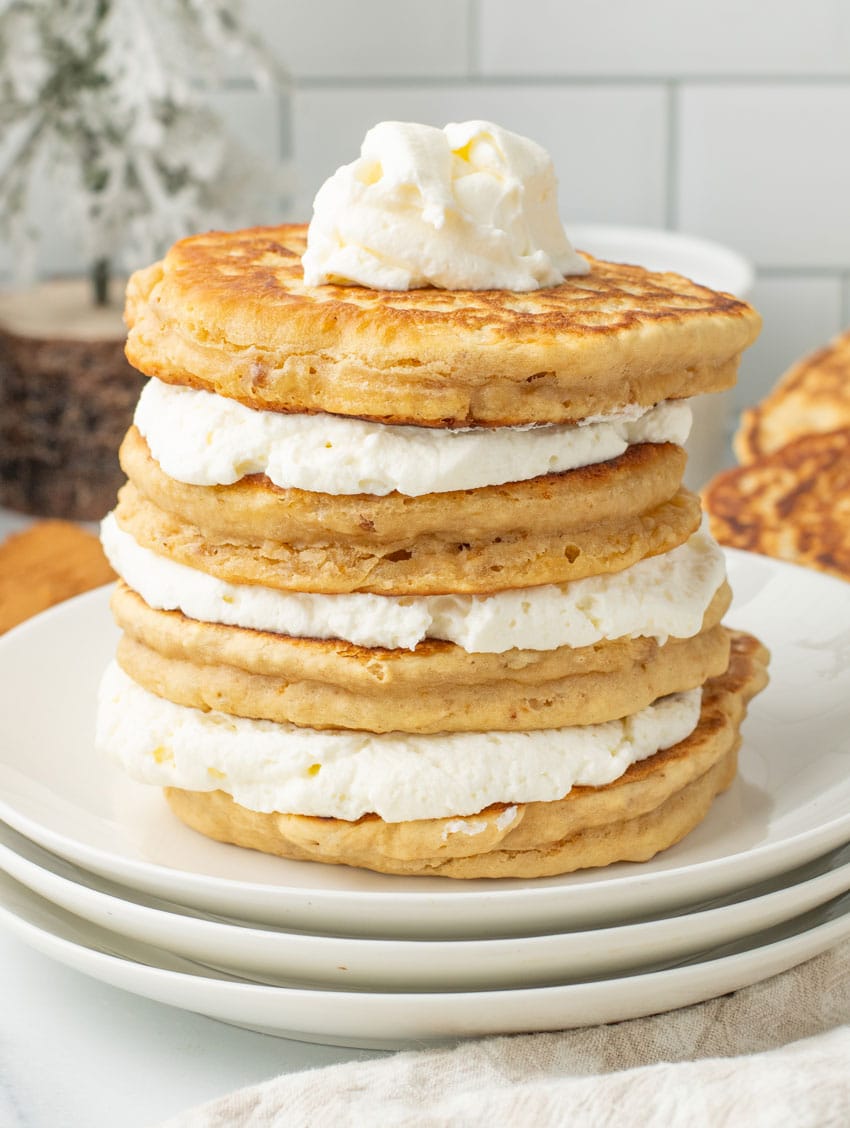 a stack of cookie butter pancakes and fluffy whipped cream on a white plate
