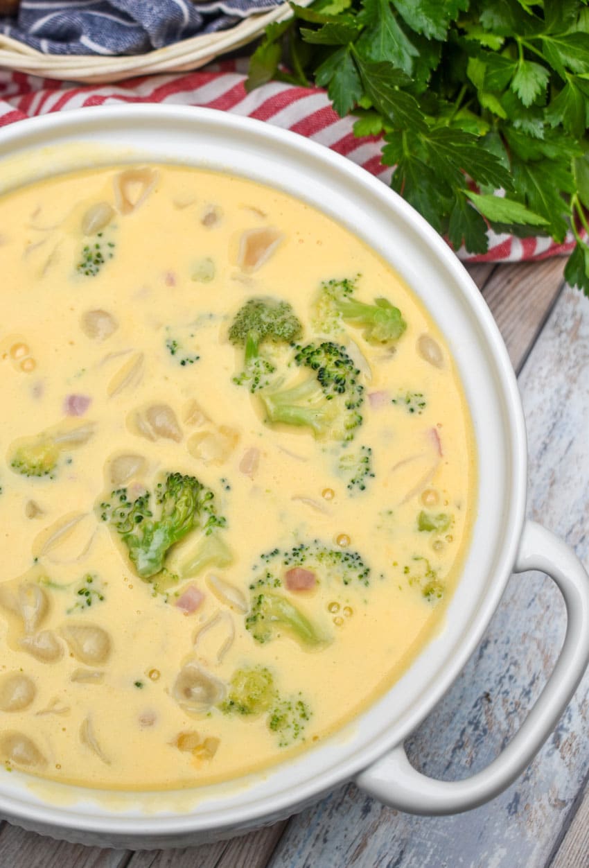 macaroni and cheese soup with ham and broccoli in a large white serving bowl