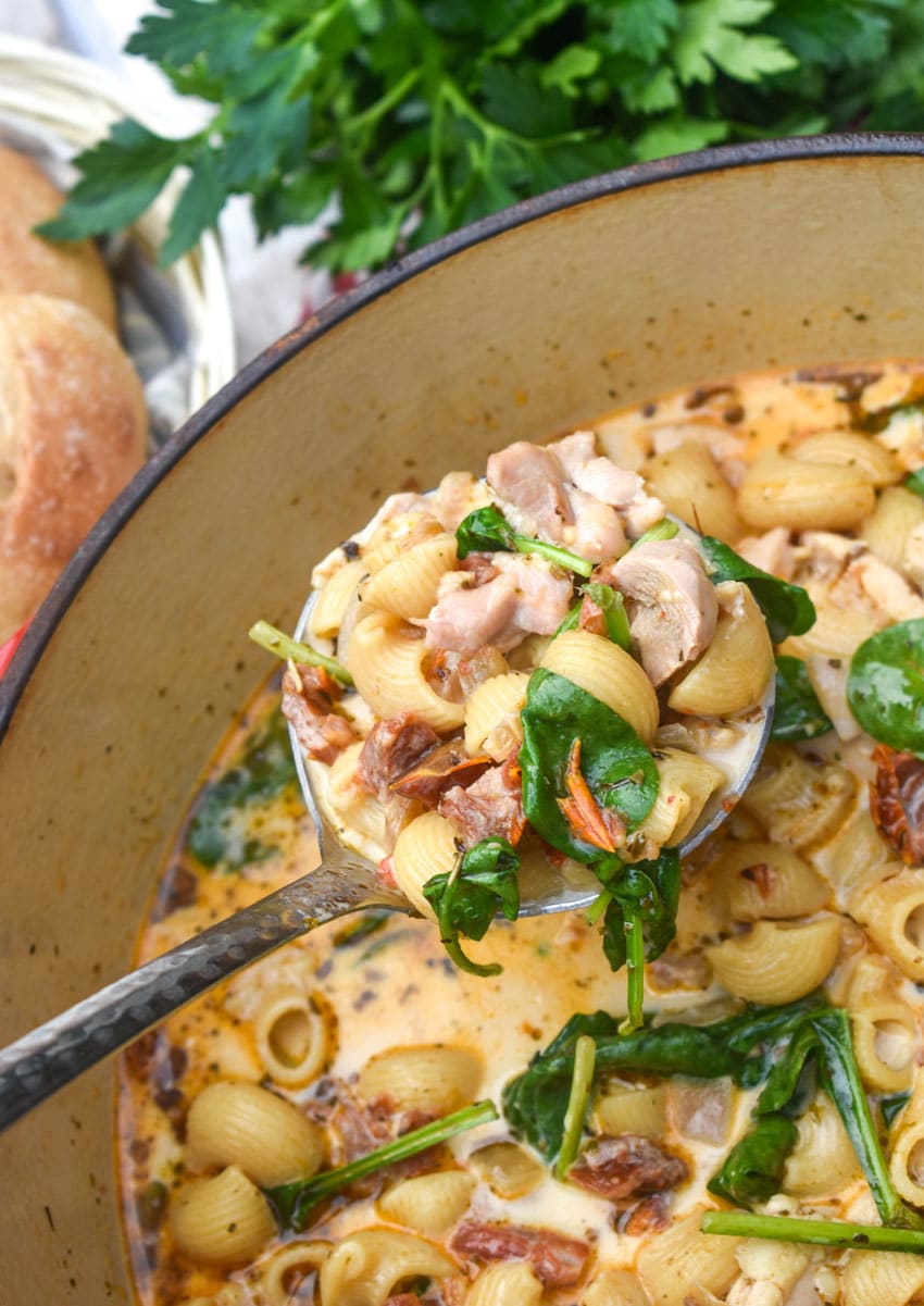 a silver ladle holding up a scoop of marry me chicken soup
