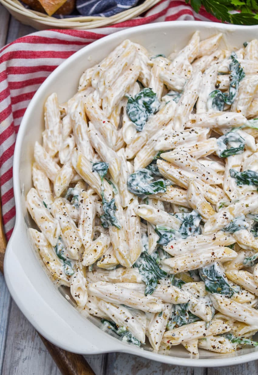 spinach dip pasta salad in a white serving bowl