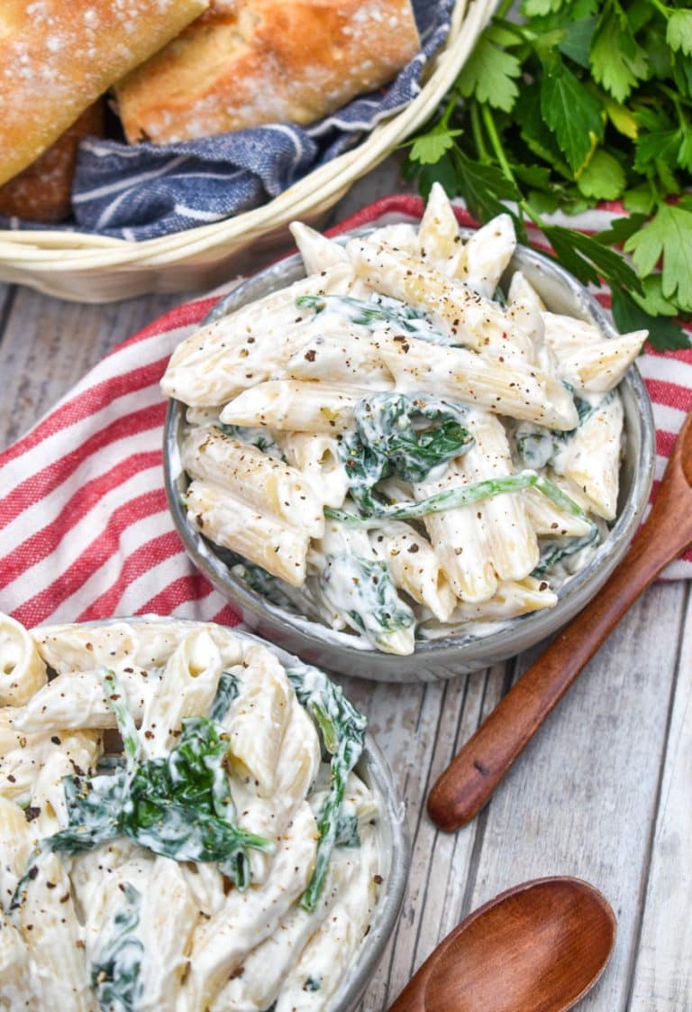 spinach dip pasta salad in two small gray bowls