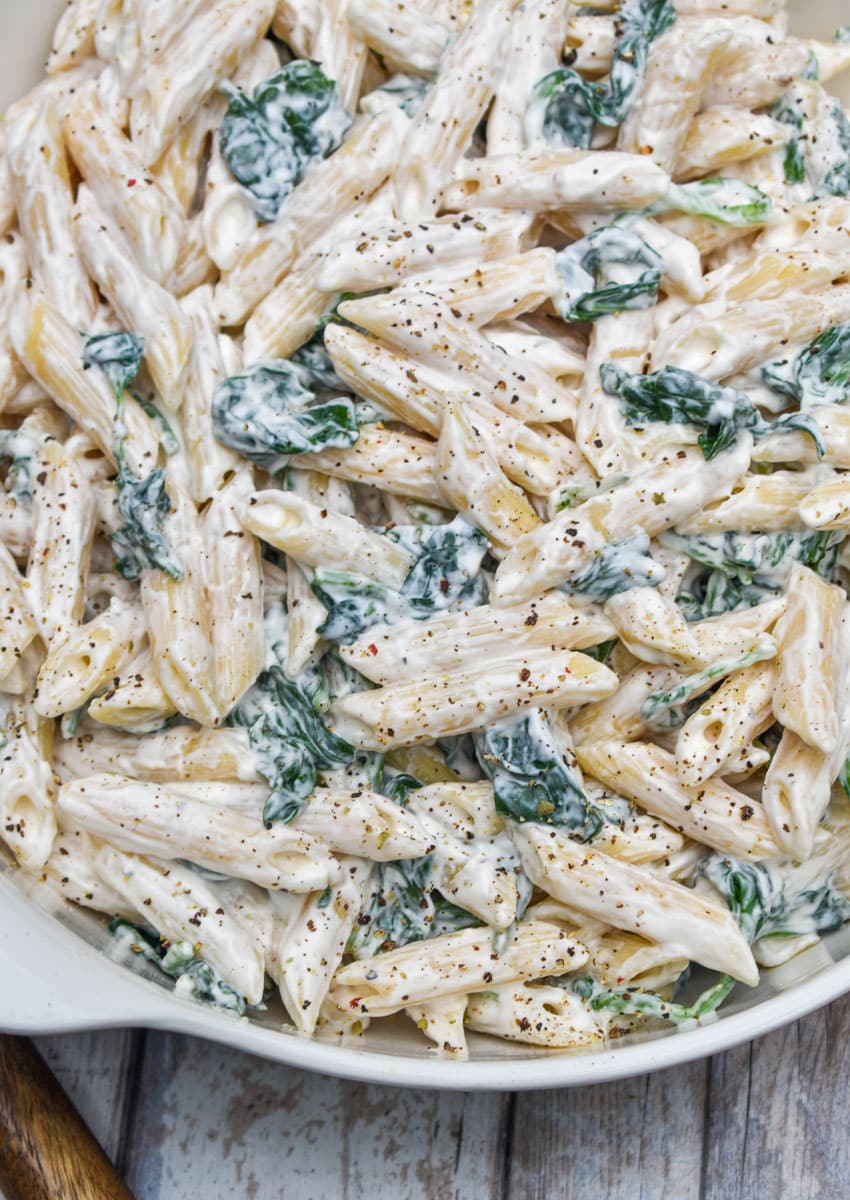 spinach dip pasta salad in a white serving bowl