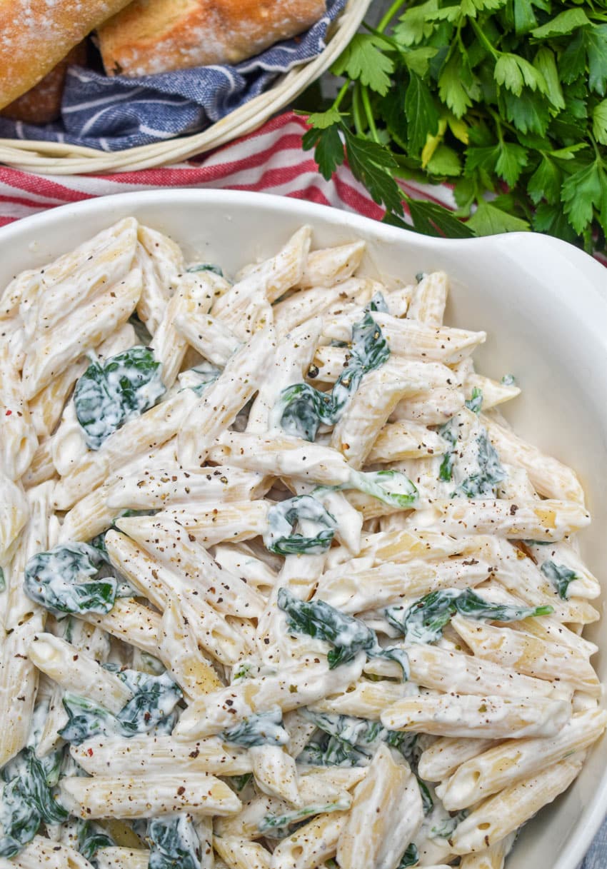 spinach dip pasta salad in a white serving bowl