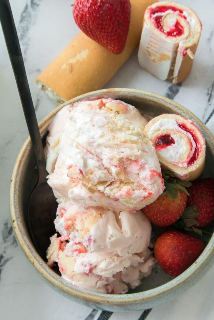 scoops of strawberry short cake rolls ice cream in a small gray bowl