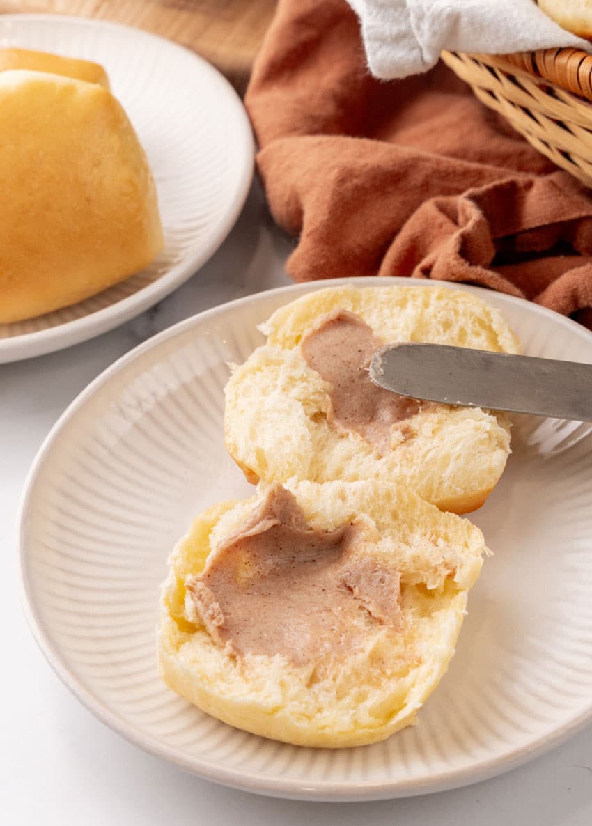 a butterknife spreading cinnamon butter over a homemade texas roadhouse roll