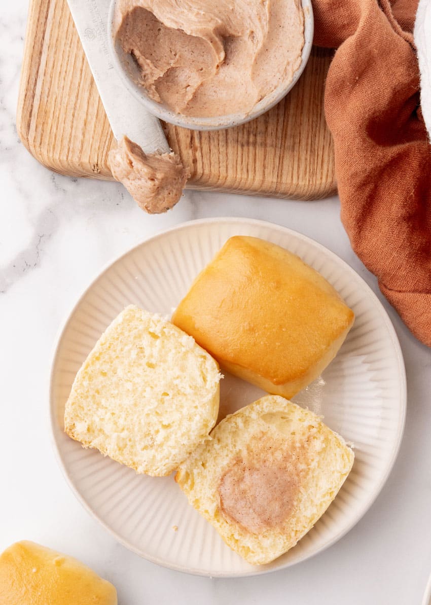 cinnamon butter topped homemade texas roadhouse rolls on a small white appetizer plate