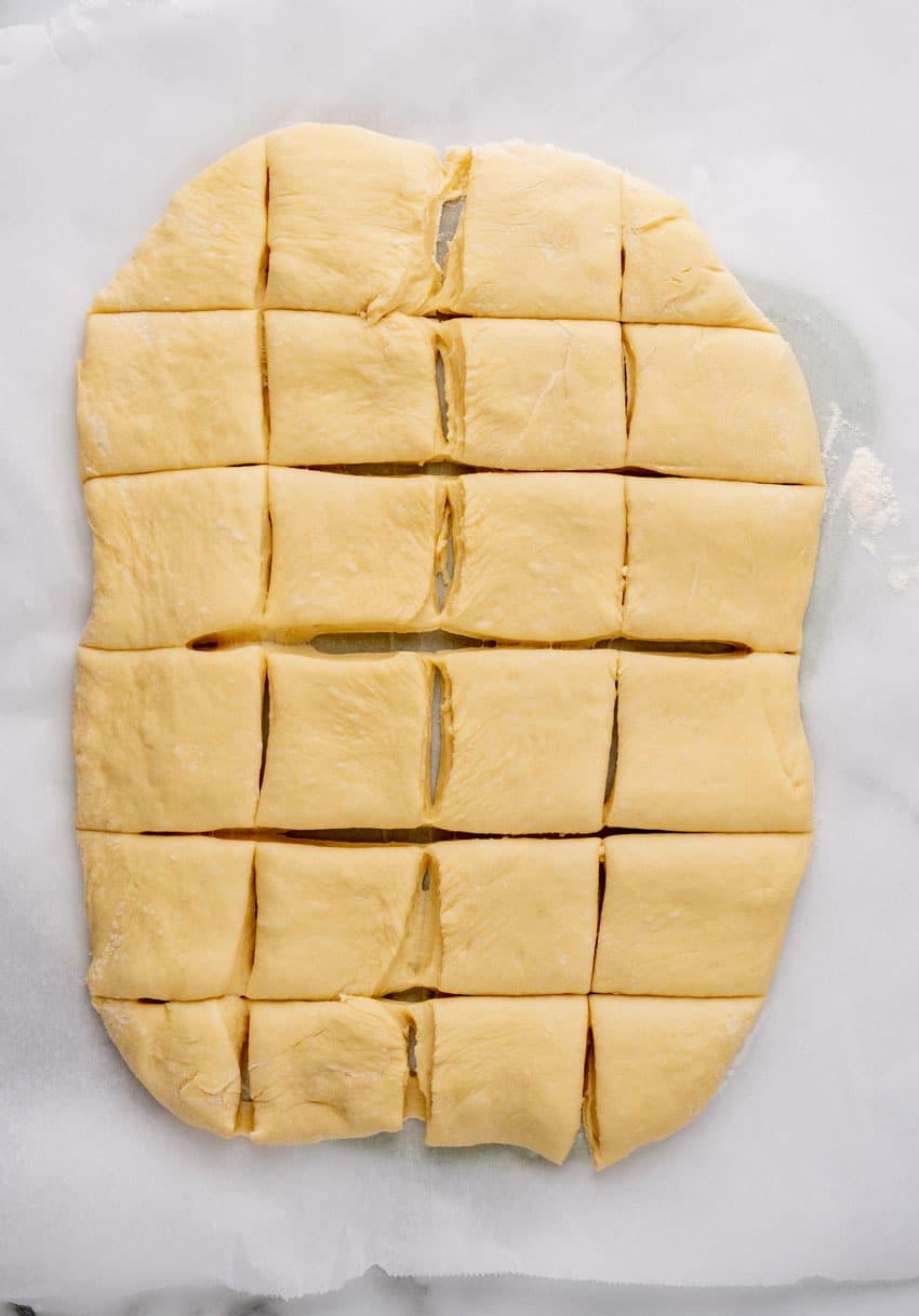 copycat texas roadhouse rolls dough rolled out and cut into squares on parchment paper