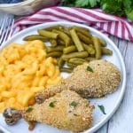 HOMEMADE SHAKE AND BAKE CHICKEN NEXT TO GREEN BEANS AND MACARONI & CHEESE ON A WHITE PLATE