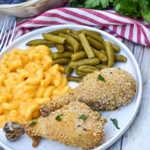 HOMEMADE SHAKE AND BAKE CHICKEN NEXT TO GREEN BEANS AND MACARONI & CHEESE ON A WHITE PLATE