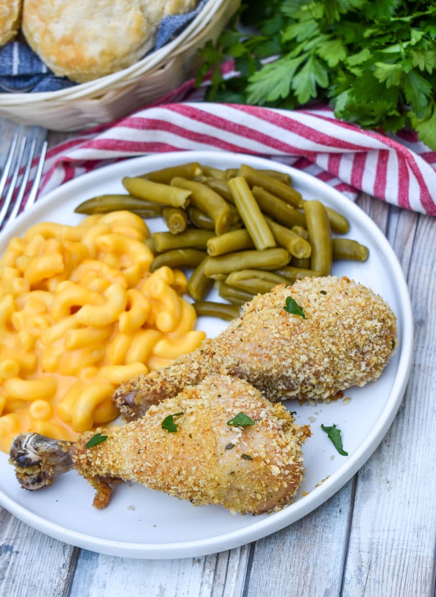 HOMEMADE SHAKE AND BAKE CHICKEN NEXT TO GREEN BEANS AND MACARONI & CHEESE ON A WHITE PLATE