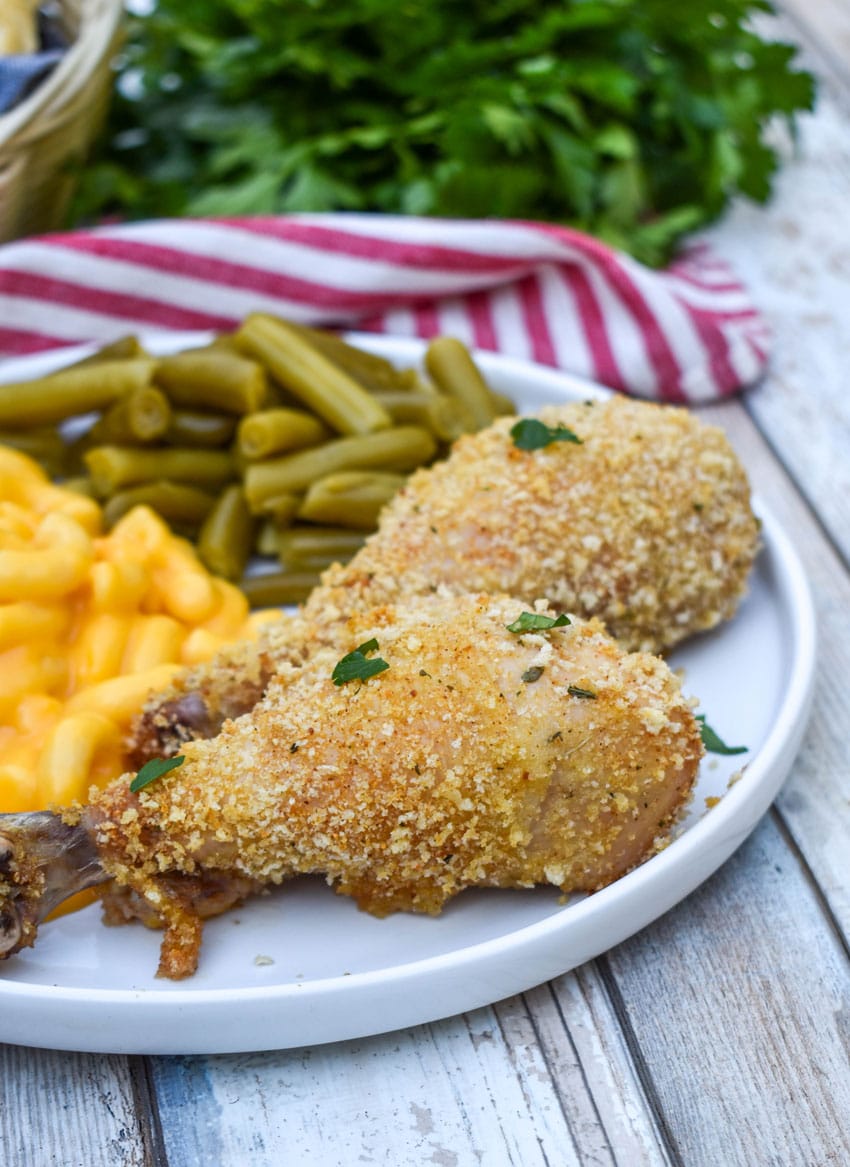 HOMEMADE SHAKE AND BAKE CHICKEN NEXT TO GREEN BEANS AND MACARONI & CHEESE ON A WHITE PLATE