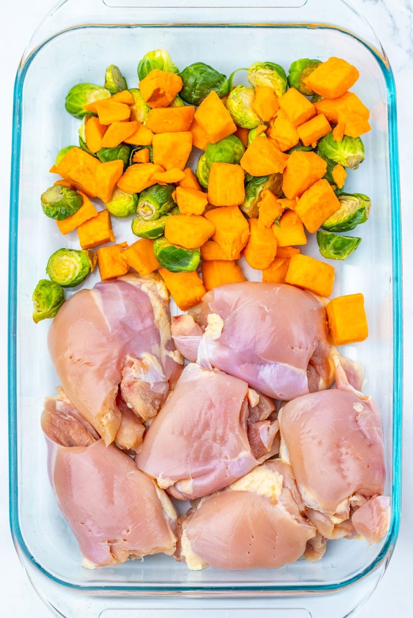 skinless chicken thighs and chopped vegetables in a glass baking dish