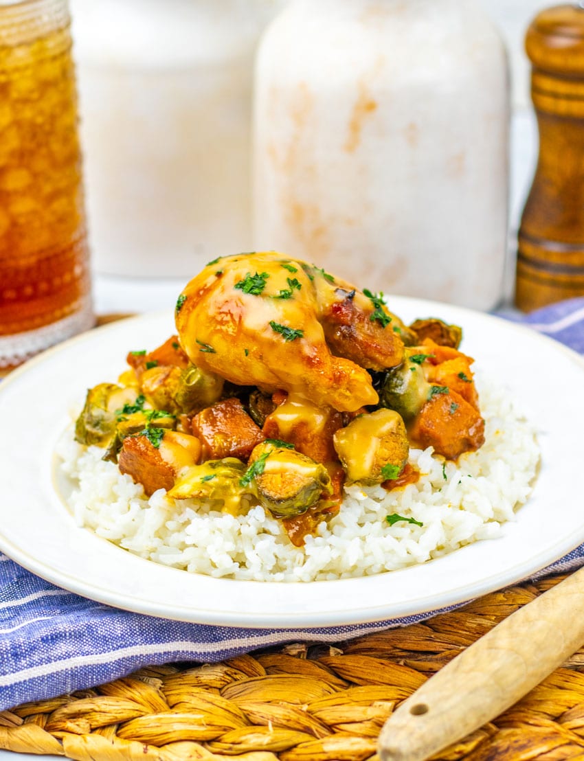 maple mustard chicken thighs and roasted vegetables over steamed rice on a white plate