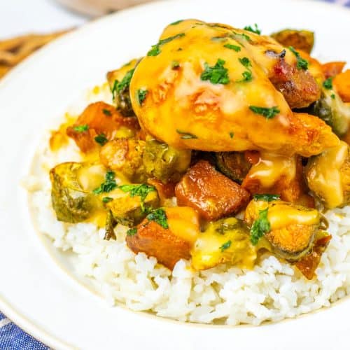 maple mustard chicken thighs and roasted vegetables over steamed rice on a white plate
