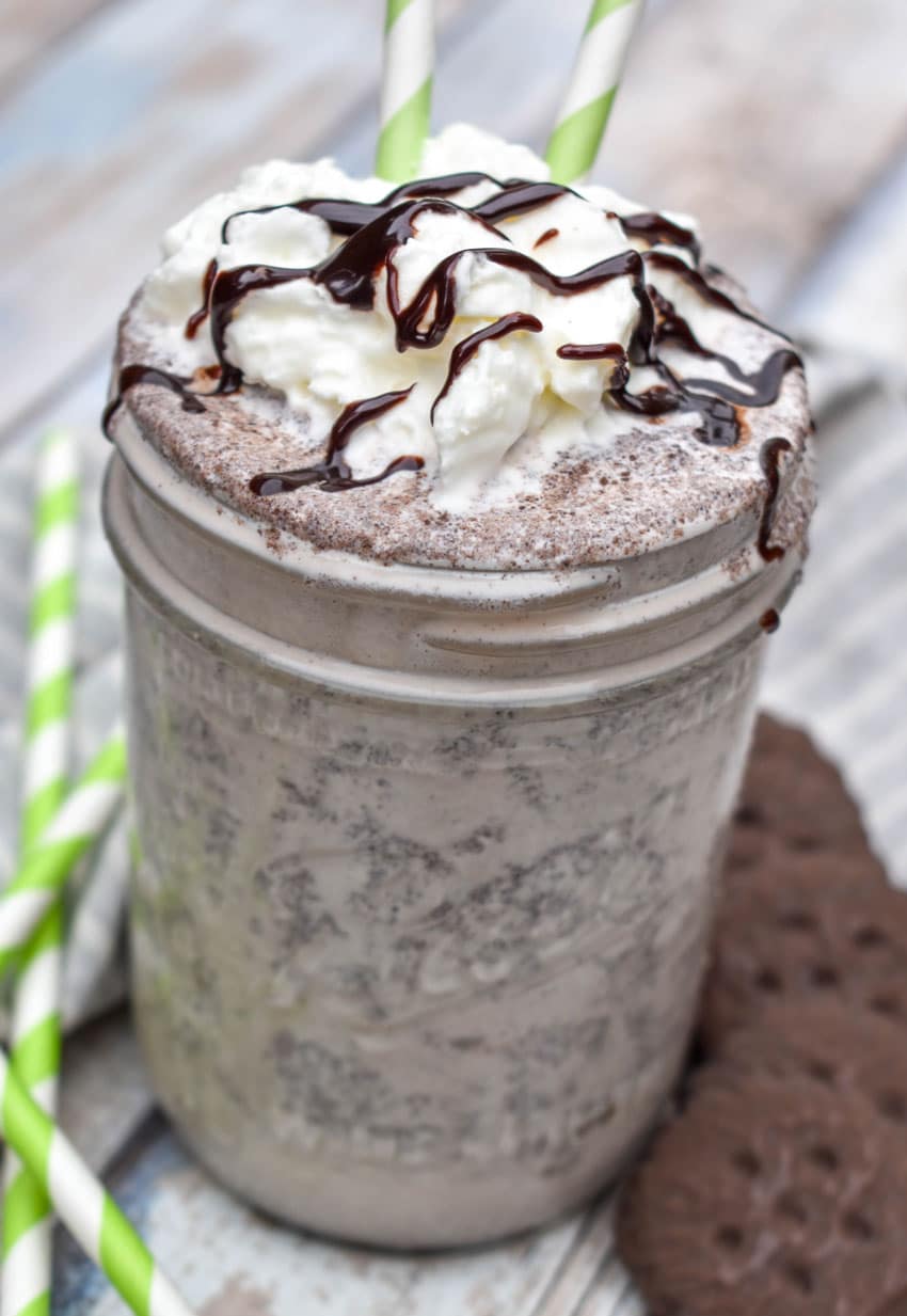 a whipped cream and chocolate syrup topped thin mint milkshake in a glass jar