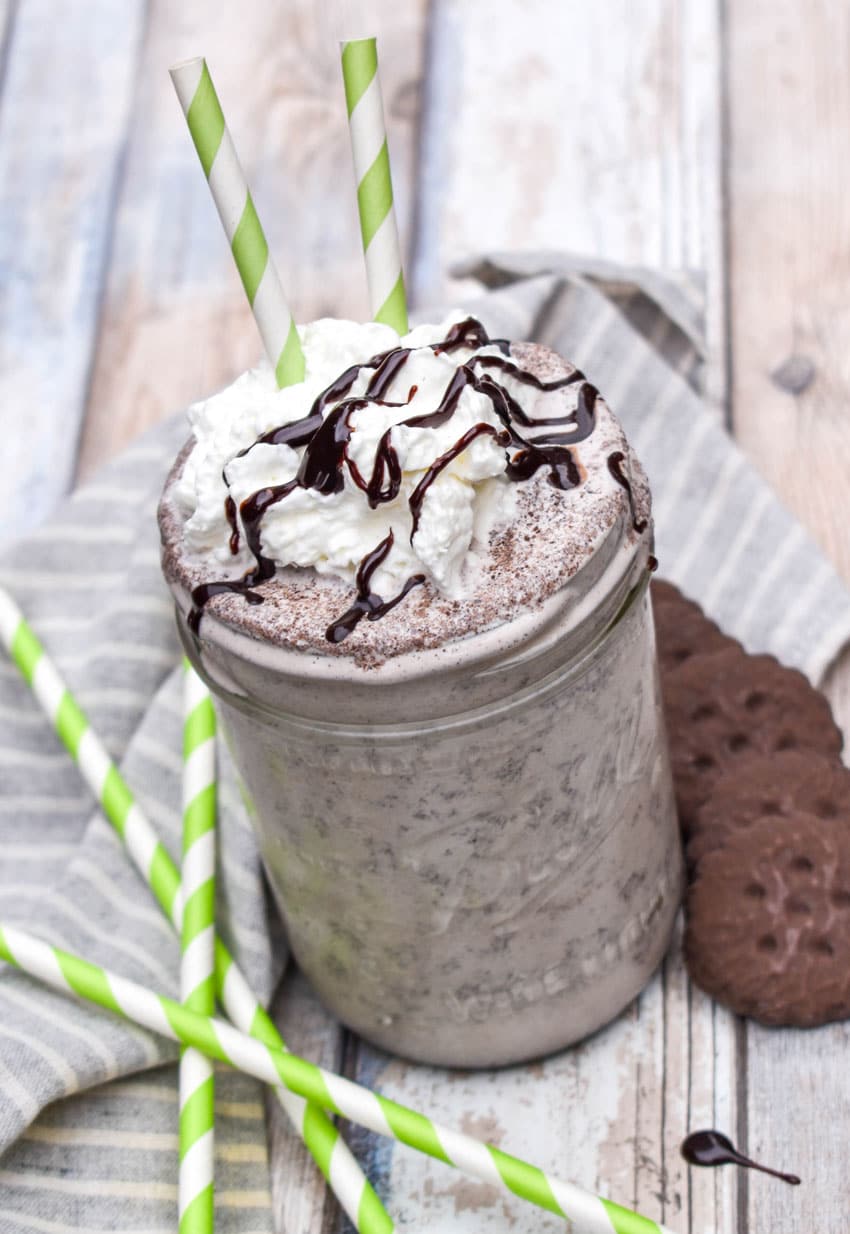 a whipped cream and chocolate syrup topped thin mint milkshake in a glass jar