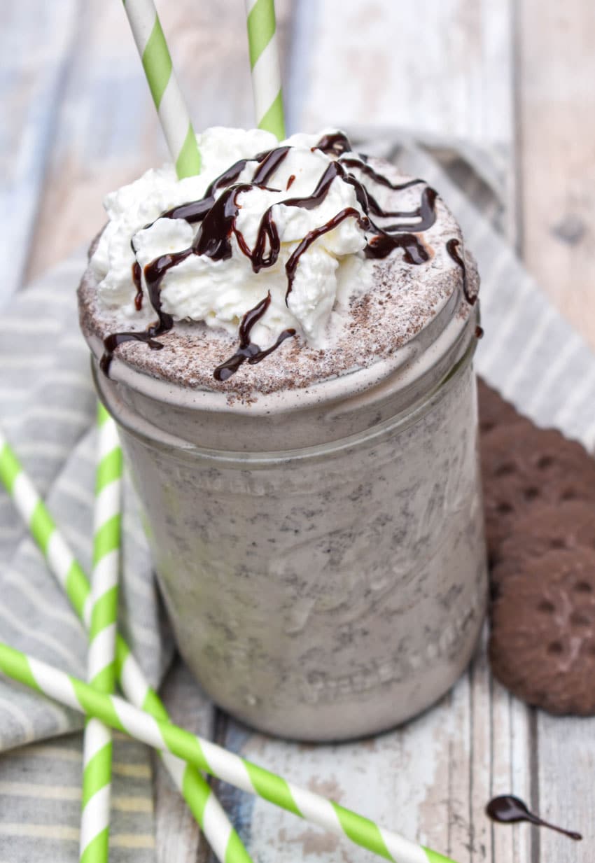 a whipped cream and chocolate syrup topped thin mint milkshake in a glass jar