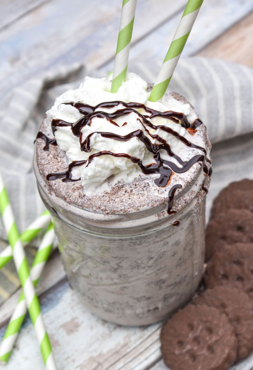 a whipped cream and chocolate syrup topped thin mint milkshake in a glass jar