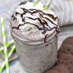a whipped cream and chocolate syrup topped thin mint milkshake in a glass jar