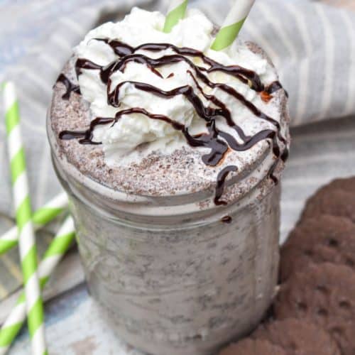 a whipped cream and chocolate syrup topped thin mint milkshake in a glass jar