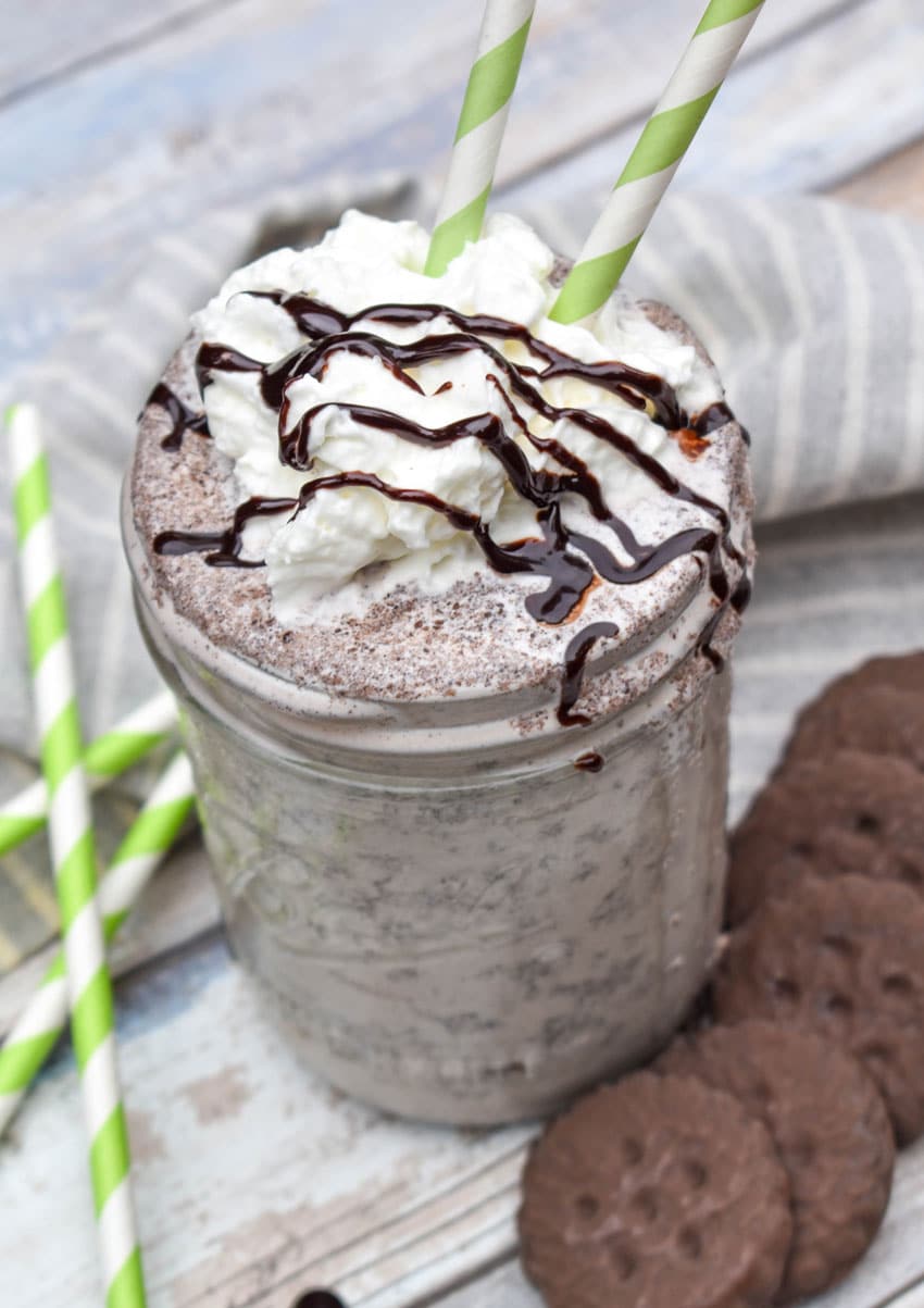 a whipped cream and chocolate syrup topped thin mint milkshake in a glass jar
