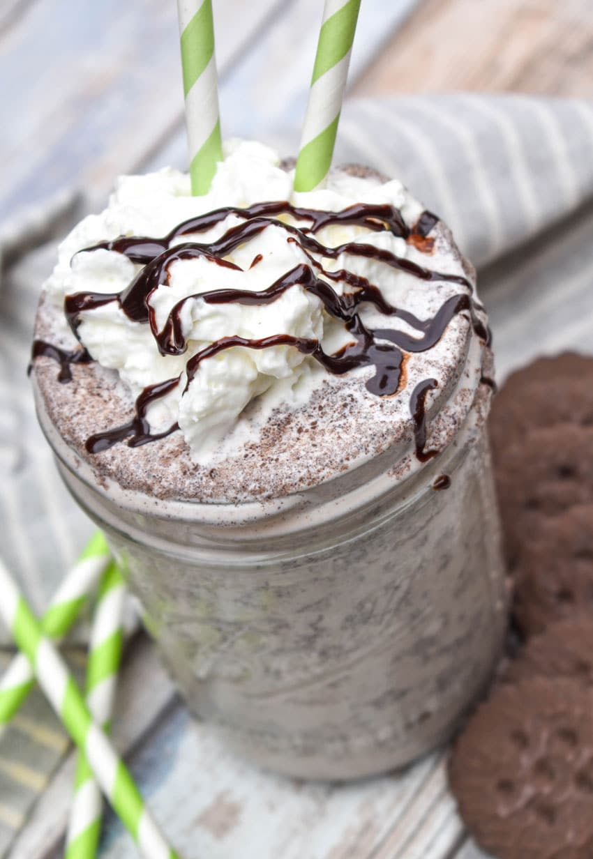 a whipped cream and chocolate syrup topped thin mint milkshake in a glass jar