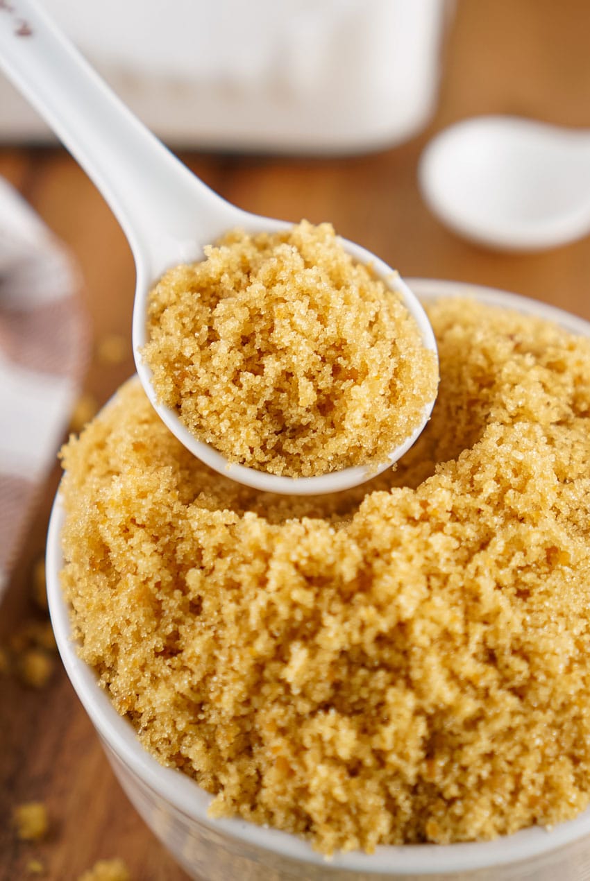 a small white spoon holding up a scoop of homemade brown sugar