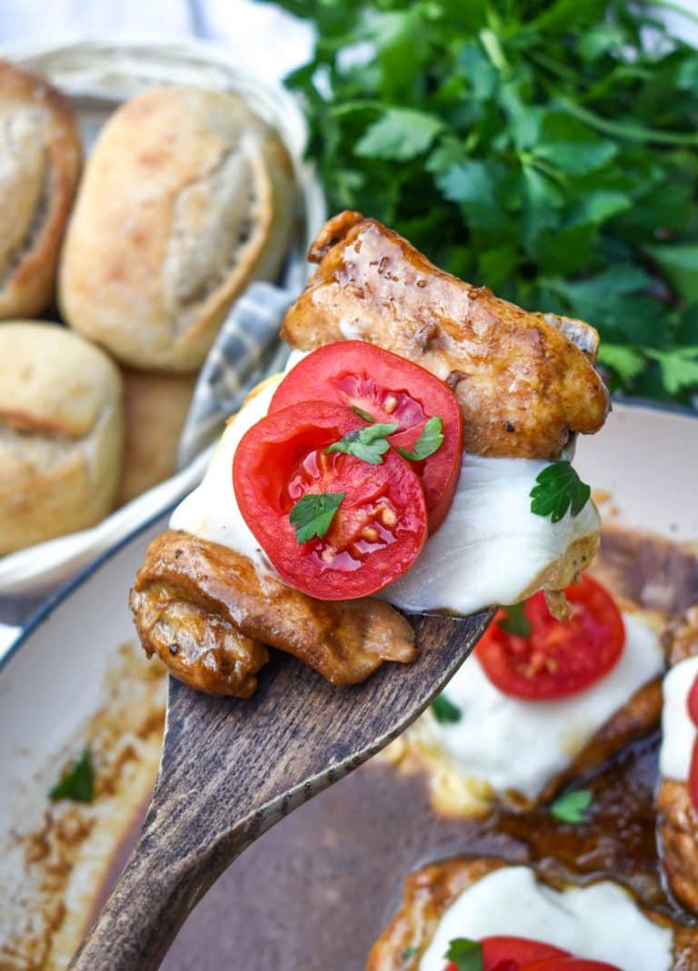 a wooden spatula holding up a slice of balsamic chicken with mozzarella