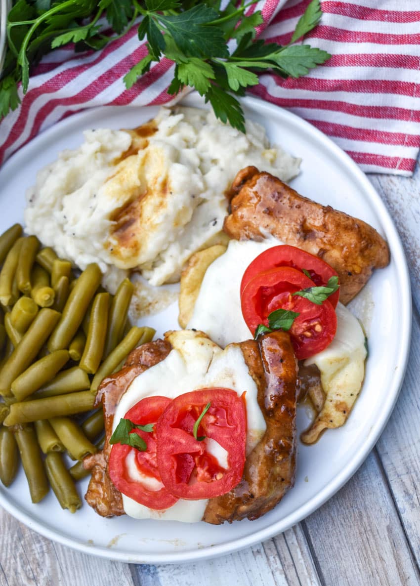 a piece of skillet balsamic chicken next to mashed potatoes and canned green beans on a white plate